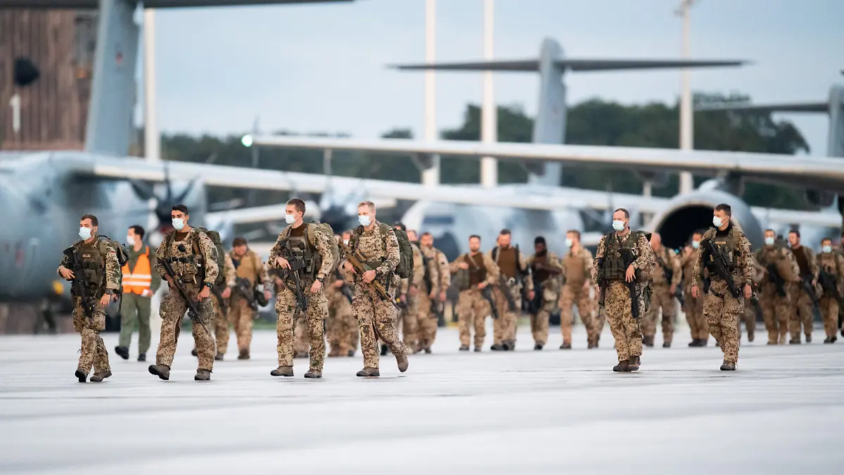 27.08.2021, Niedersachsen, Wunstorf: Soldaten steigen aus den Transportflugzeugen A400M der Bundeswehr und dem Airbus A310 der Luftwaffe nach der Landung auf dem niedersächsischen Stützpunkt Wunstorf. Die ersten Soldaten der Bundeswehr sind von ihrer Evakuierungsmission in Afghanistan nach Deutschland zurückgekehrt. Auf dem Luftwaffenstützpunkt Wunstorf bei Hannover landeten am Freitagabend kurz vor 20.00 Uhr drei Militärmaschinen. Für den Rückflug der Soldaten nach Deutschland wurden ein Airbus A310 der Luftwaffe und zwei Militärtransporter A400M eingesetzt . Die Einsatzkräfte waren in Taschkent gestartet, der Hauptstadt von Usbekistan. Dort hatte die Bundeswehr ein Drehkreuz eingerichtet, um in kurzen Shuttleflügen Deutsche und bedrohte Afghanen aus Kabul auszufliegen. Foto: Daniel Reinhardt/dpa +++ dpa-Bildfunk +++