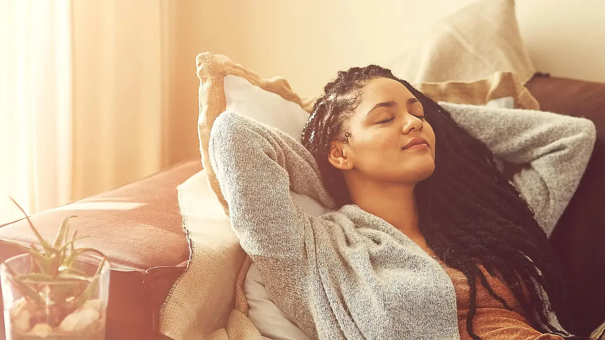 Shot of a young woman sleeping on her living room sofa