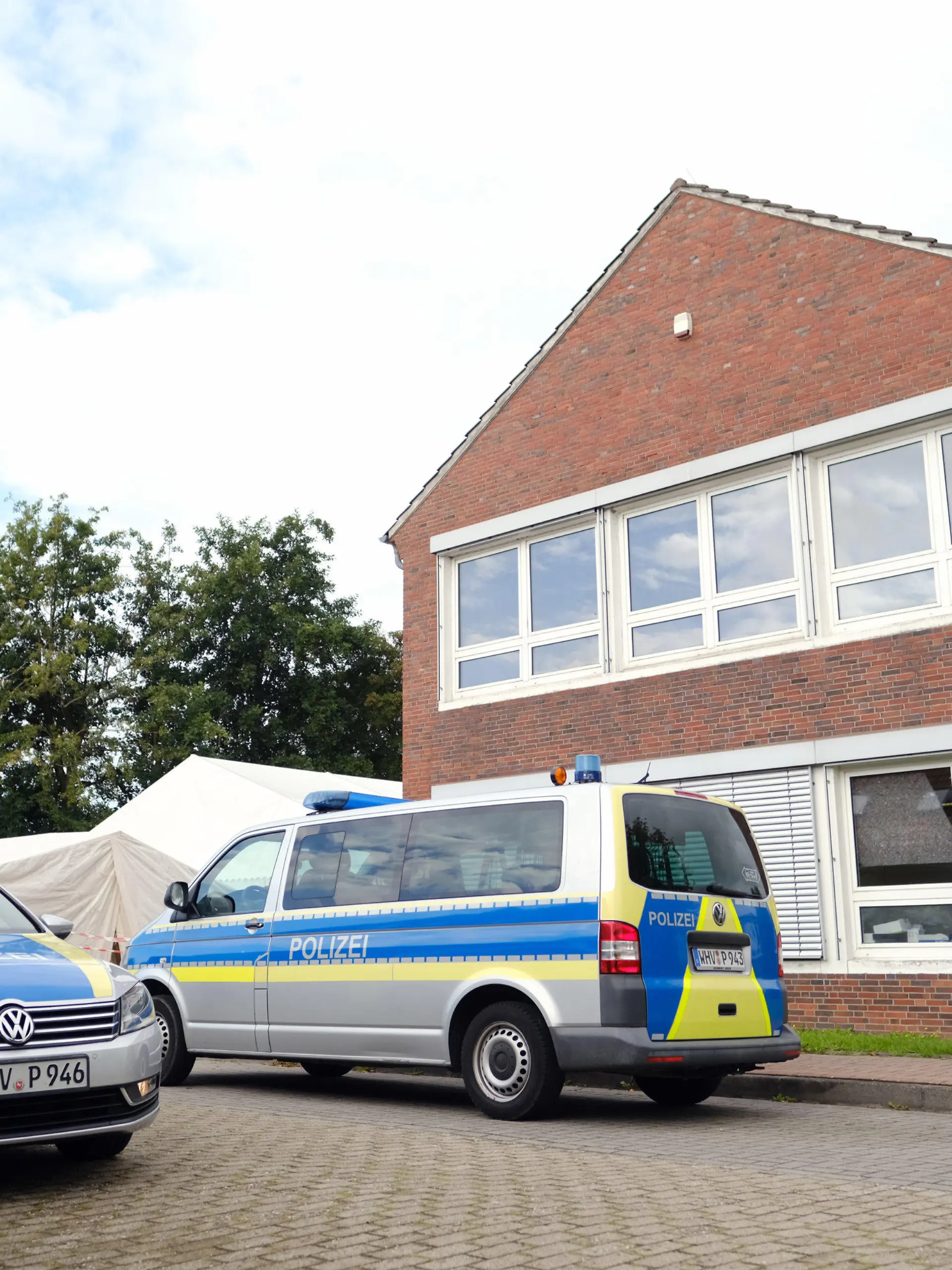 26.08.2021, Niedersachsen, Schortens: Polizeiwagen stehen vor dem Impfzentrum. In den Morgenstunden durchsuchten Beamte mehrere Gebäude des Deutschen Roten Kreuzes (DRK) in Friesland. Die Soko "Vakzin" hat bei ihren Ermittlungen weitere Unregelmäßigkeiten festgestellt.      (zu dpa "Durchsuchungen bei Ermittlungen zu Kochsalz-Injektionen") Foto: Markus Hibbeler/dpa +++ dpa-Bildfunk +++