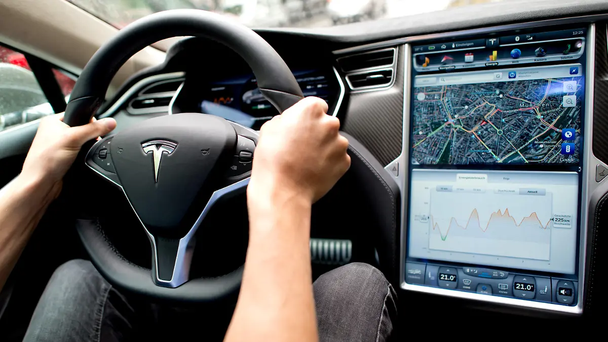 ARCHIV - 17.08.2015, Bayern, München: Ein Mann sitzt in einem Tesla Model S am Lenkrad, neben ihm ein großer Monitor im Armaturenbrett.   
(zu dpa "Behörde prüft Fehlfunktion von Tesla-Bildschirm") Foto: picture alliance / dpa +++ dpa-Bildfunk +++
