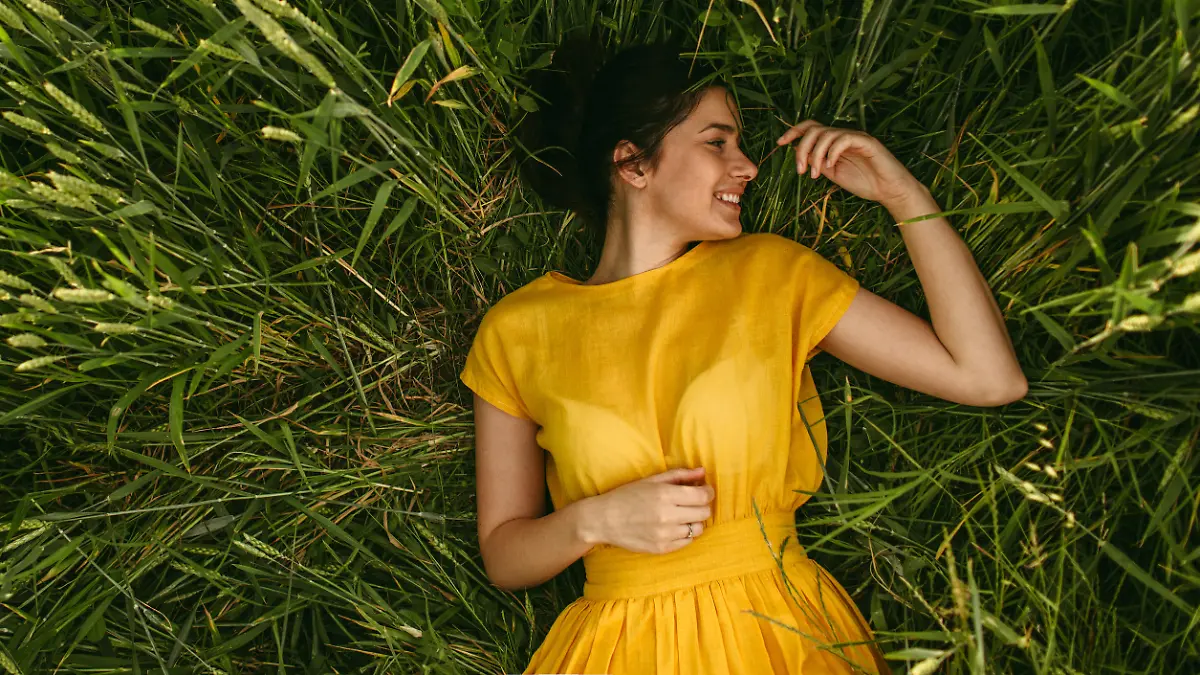 Young girl holding chamomile plant in her hands and enjoying the calm meadow