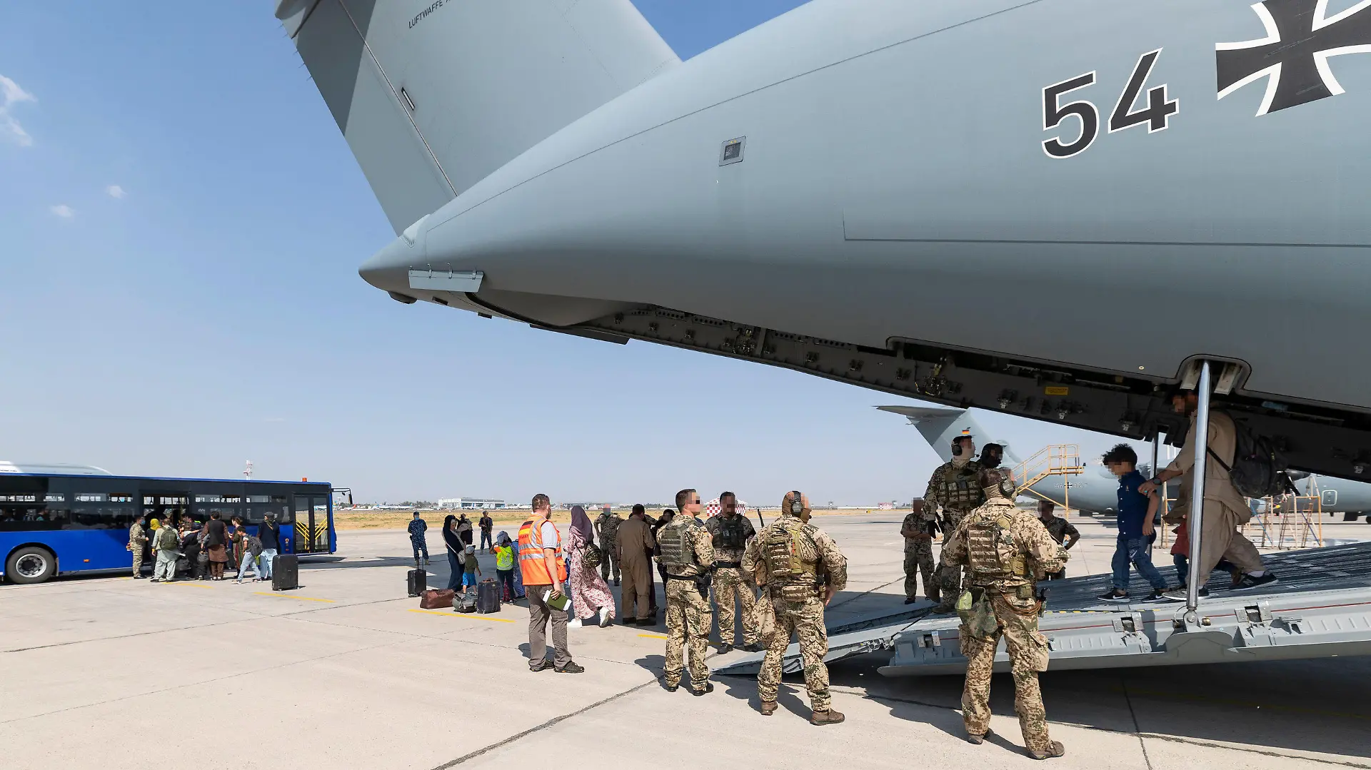 HANDOUT - 26.08.2021, Afghanistan, Taschkent: Schutzbedürftige Menschen gehen kurz nach dem Flug aus Kabul zu einem Bus. Die Bundeswehr hat ihre Evakuierungsmission für Deutsche und einheimische Ortskräfte in Afghanistan am Donnerstagmorgen fortgesetzt. Foto: Marc Tessensohn/Bundeswehr/dpa - ACHTUNG: Nur zur redaktionellen Verwendung im Zusammenhang mit der aktuellen Berichterstattung und nur mit vollständiger Nennung des vorstehenden Credits ACHTUNG: Bei den von der Bundeswehr bereitgestellten Fotos waren Angehörige der Bundeswehr und andere Soldaten bereits gepixelt. Die Pixelung der Zivilisten hat dpa zum Schutz ihrer Persönlichkeitsrechte vorgenommen. +++ dpa-Bildfunk +++