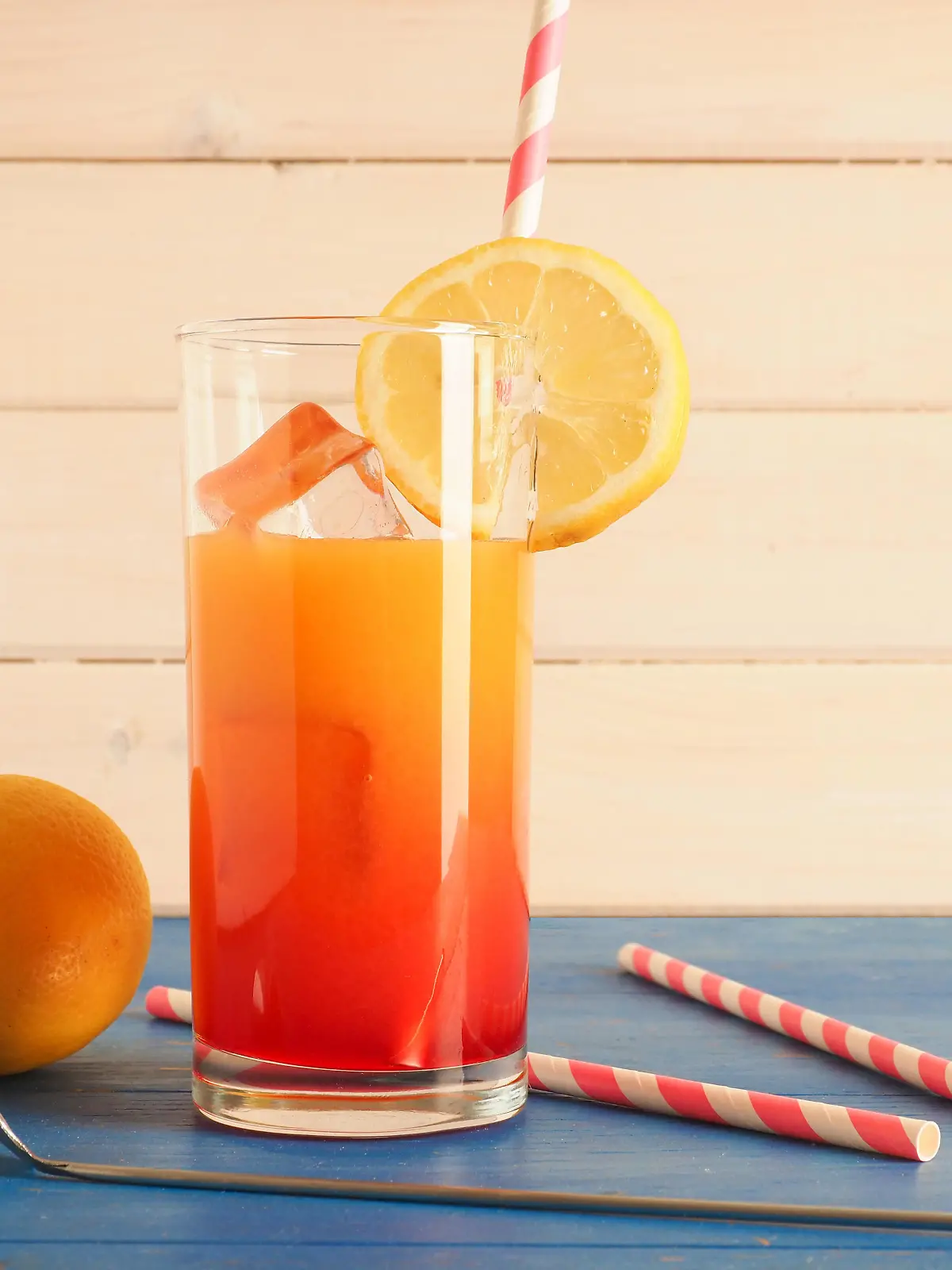 Non alcoholic cocktail with orange and lemon juice and grendine syrup on ice, tasty summer drink on a wooden background