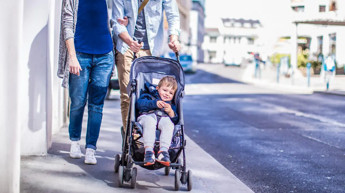 Photo of cool couple and their baby boy having a walk