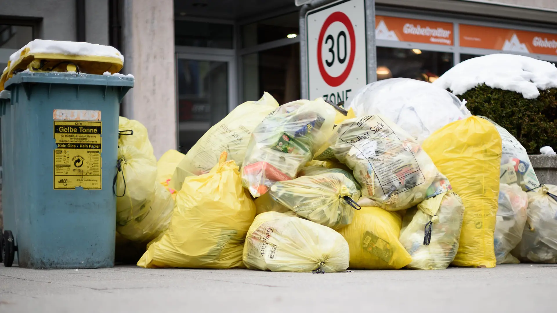 22.02.2018, Baden-Württemberg, Ulm: Mülltonnen und gelbe Säcke mit Kunststoff-Abfällen (Grüner Punkt) stapeln sich auf einem Fußweg. Foto: Sina Schuldt/dpa