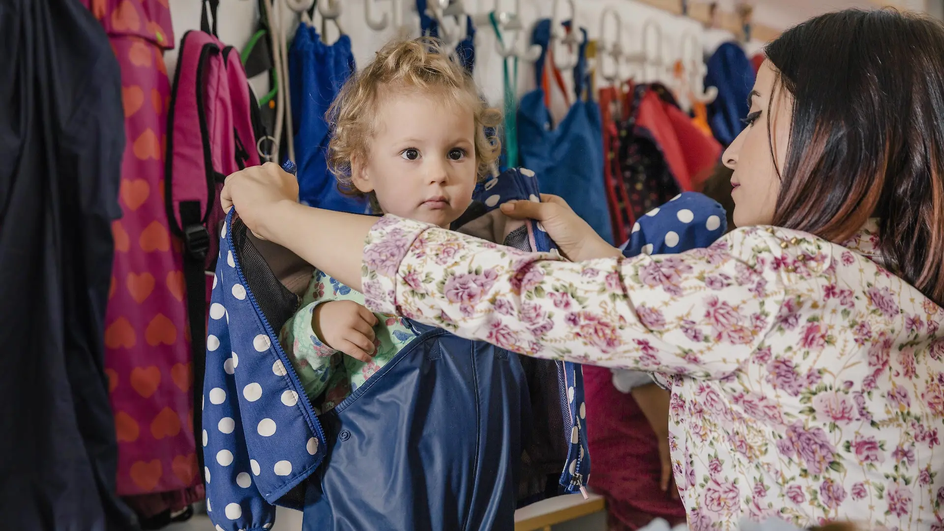 Pre-school teacher helping girl putting on mud pants in kindergarten model released Symbolfoto property released PUBLICATIONxINxGERxSUIxAUTxHUNxONLY MFF04111