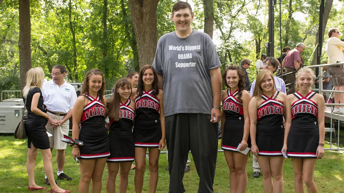 FILE- In this Aug. 15, 2011 photo, Seven-foot, eight-inch tall, Igor Vovkovinskiy, the self proclaimed biggest supporter of President Barack Obama, takes a photo with cheerleaders from the Cannon Falls high school prior to a President Barack Obama town hall event at Lower Hannah's Bend Park, in Cannon Falls, Minn. Vovkovinskiy, the tallest man in the United States, has died in Minnesota. He was 38. His family says the Ukrainian-born Vovkovinskiy died of heart disease Friday, Aug. 20, 2021, at the Mayo Clinic in Rochester. (AP Photo/Nati Harnik/file)