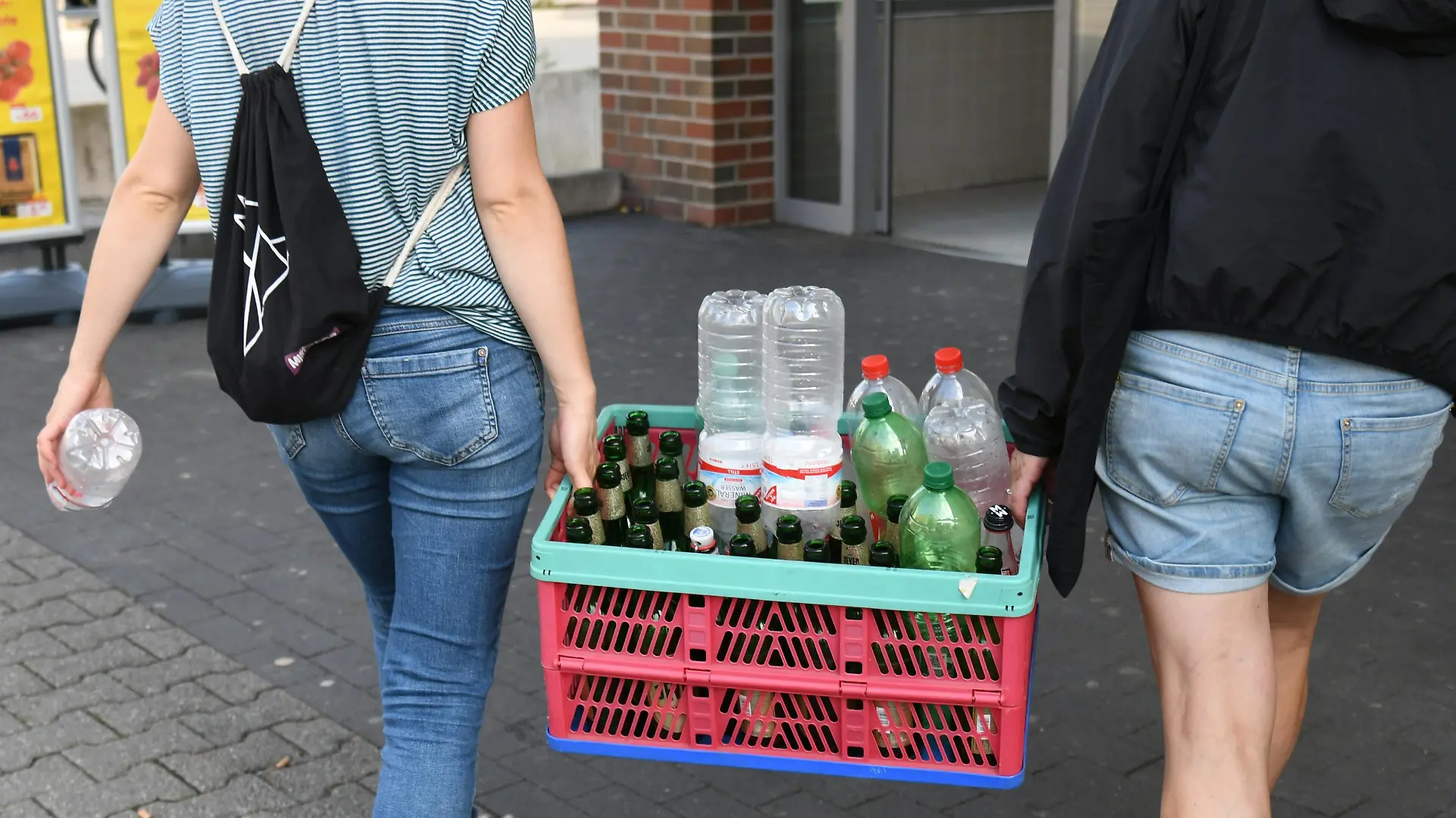 Zwei Frauen tragen eine Kiste mit Leergut in einen Supermarkt in Berlin, um die Pfandflaschen zurückzugeben. Foto: Winfried Rothermel