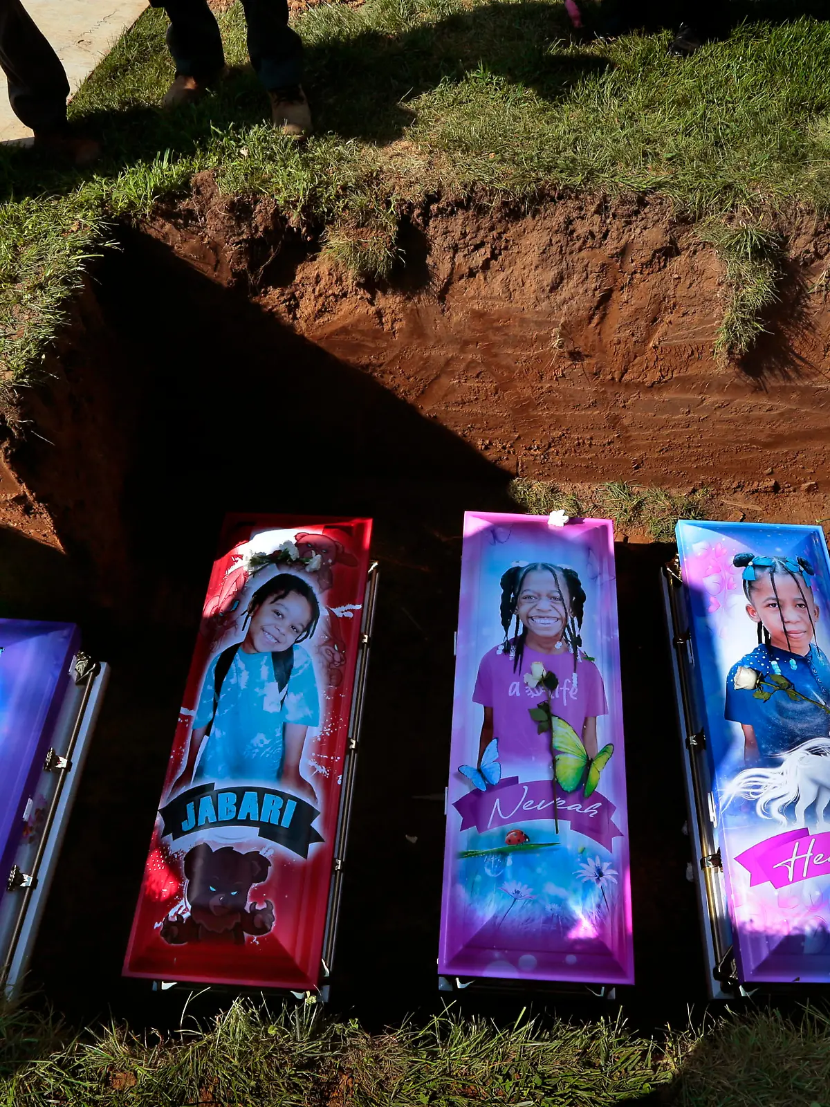 Cemetery workers prepare to cover the caskets of five children at Sunset Gardens of Memory Cemetery in Millstadt, Ill. on Saturday, Aug. 21, 2021 after they died in a predawn fire in East St. Louis on Aug. 6. Sabrina Dunigan's five children - Loy'el Dunigan, 2, Jabari Johnson 4, twin sisters Heaven and Neveah "Veah" Dunigan, 8, and Deontae Davis, 9, were killed in the fire while Dunigan was picking up her boyfriend. Their grandfather and his wife jumped from the apartment's second floor. (Robert Cohen/St. Louis Post-Dispatch via AP)