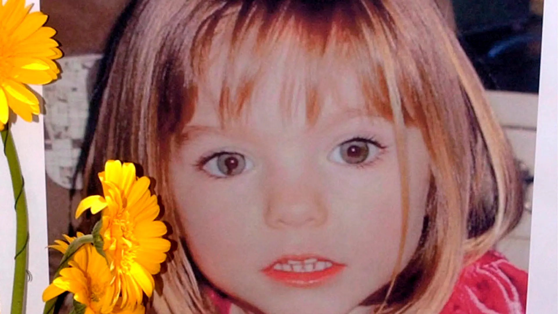 ARCHIV - 12.05.2007, Portugal, Lagos: Blumen stehen vor einem Bild, das die verschwundenen Madeleine McCann (Maddie) auf einem Foto zeigt, das ihre Eltern im Zusammenhang mit dem Verschwinden des Kindes veröffentlich haben. Im Fall der vor mehr als 13 Jahren verschwundenen Maddie ist nach Aussage der Ermittler noch völlig offen, ob es 2021 eine Anklage gegen den Mordverdächtigen geben wird. (zu dpa: "Ermittler wollen Maddies Schicksal klären - Ergebnisse aber offen") Foto: Luis Forra/LUSA FILE/dpa +++ dpa-Bildfunk +++