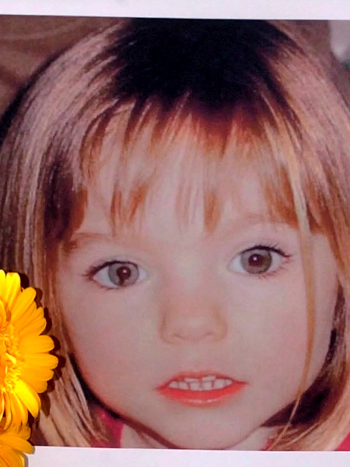 ARCHIV - 12.05.2007, Portugal, Lagos: Blumen stehen vor einem Bild, das die verschwundenen Madeleine McCann (Maddie) auf einem Foto zeigt, das ihre Eltern im Zusammenhang mit dem Verschwinden des Kindes veröffentlich haben. Im Fall der vor mehr als 13 Jahren verschwundenen Maddie ist nach Aussage der Ermittler noch völlig offen, ob es 2021 eine Anklage gegen den Mordverdächtigen geben wird. (zu dpa: "Ermittler wollen Maddies Schicksal klären - Ergebnisse aber offen") Foto: Luis Forra/LUSA FILE/dpa +++ dpa-Bildfunk +++