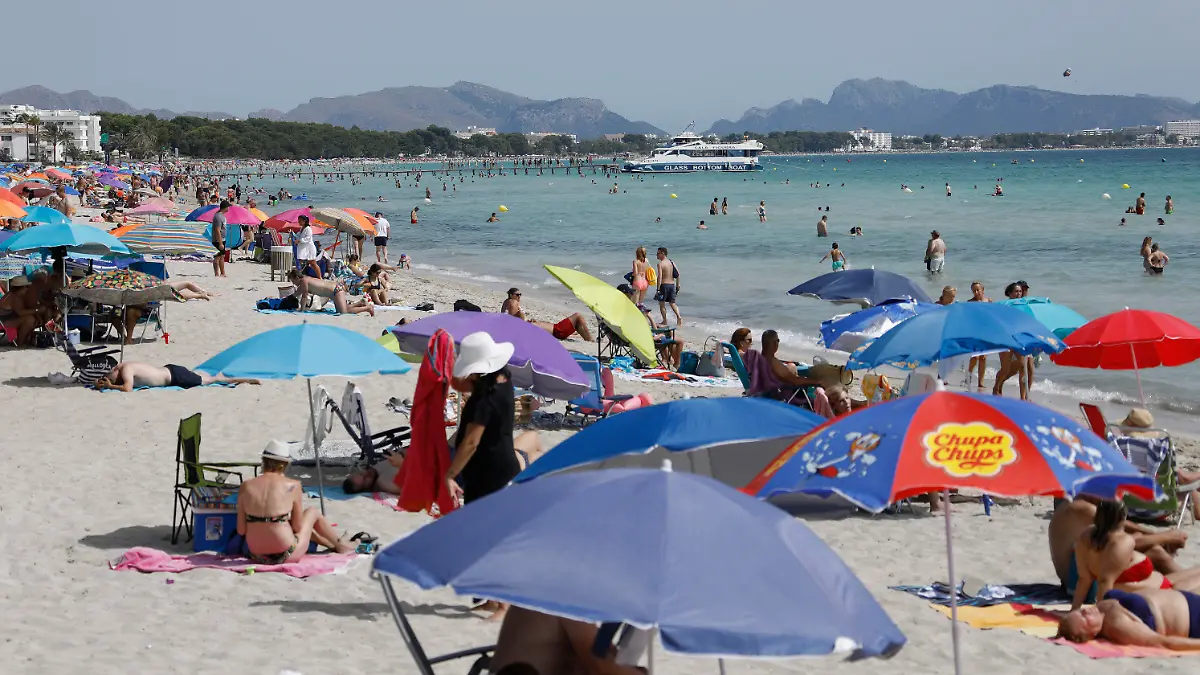 11.07.2021, Spanien, -: Unter bunten Sonnenschirmen genießen viele Menschen Sonne, Sand und Meer am Strand von Playa de Muro im Norden von Mallorca. Die Bundesregierung hat ganz Spanien mit Mallorca und den Kanaren angesichts rapide ansteigender Corona-Zahlen zum Risikogebiet erklärt. Die praktischen Auswirkungen für Mallorca-Urlauber halten sich zunächst aber in Grenzen. Foto: Clara Margais/dpa +++ dpa-Bildfunk +++