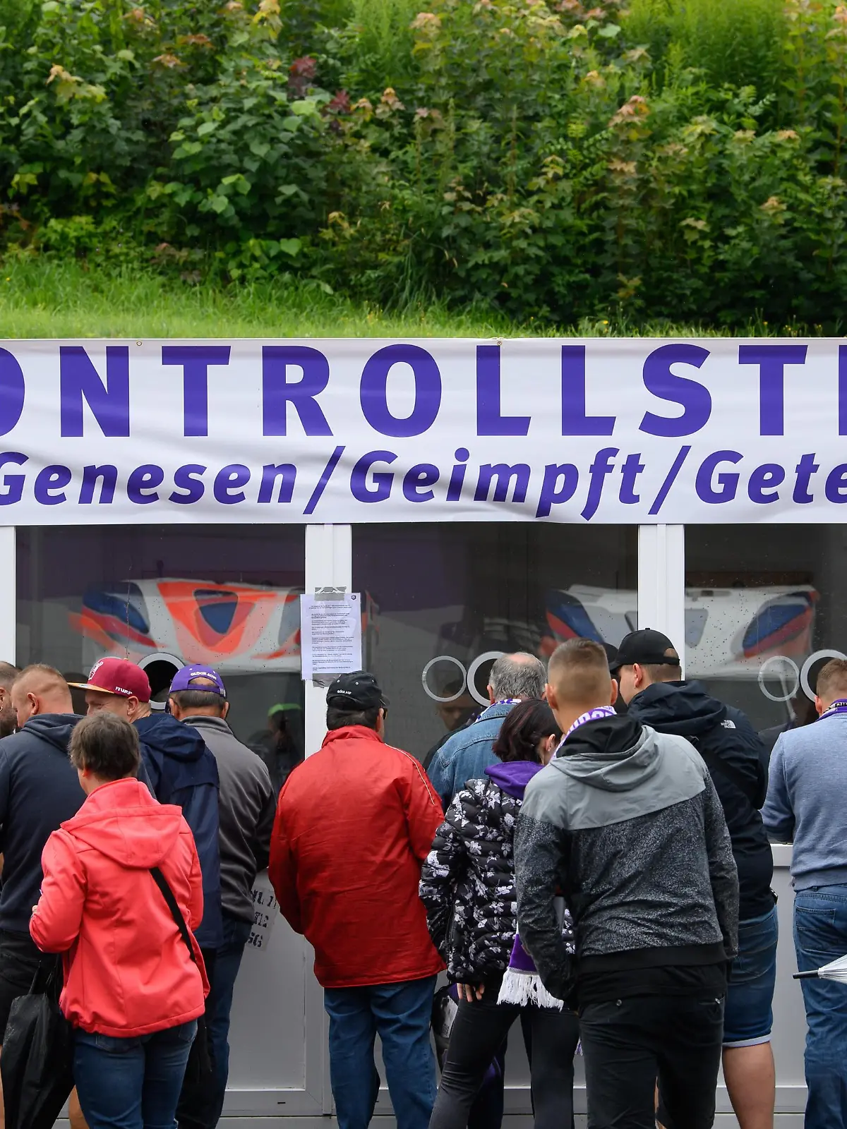 Fußball: 2. Bundesliga, FC Erzgebirge Aue - FC St. Pauli, 2. Spieltag, im Erzgebirgsstadion. Auer Fans stehen vor dem Stadion an einer "Kontrollstelle für Genesen, Geimpft und Getestet" an, um sich zu registrieren.