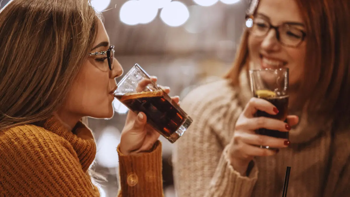 Close-up shot of two women having a refreshing drink at the bar.