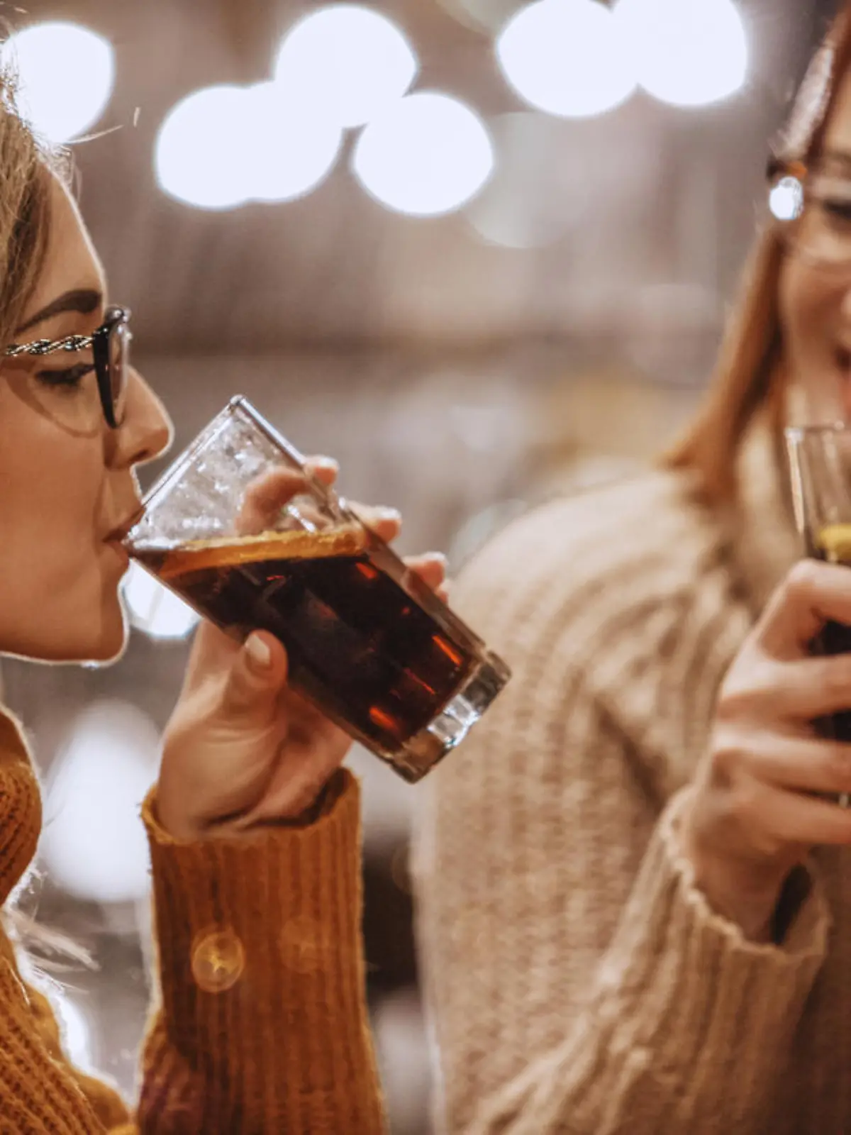 Close-up shot of two women having a refreshing drink at the bar.