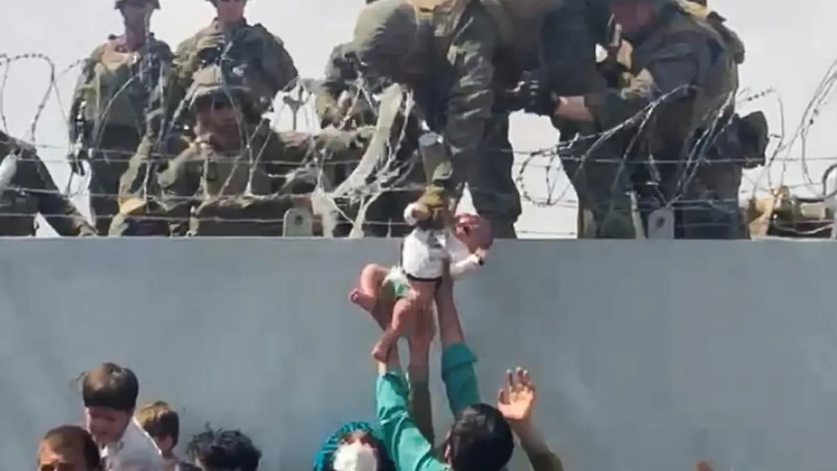 FILE PHOTO: A baby is handed over to the American army over the perimeter wall of the airport for it to be evacuated, in Kabul, Afghanistan, August 19, 2021. OMAR HAIDARI/via REUTERS/File Photo