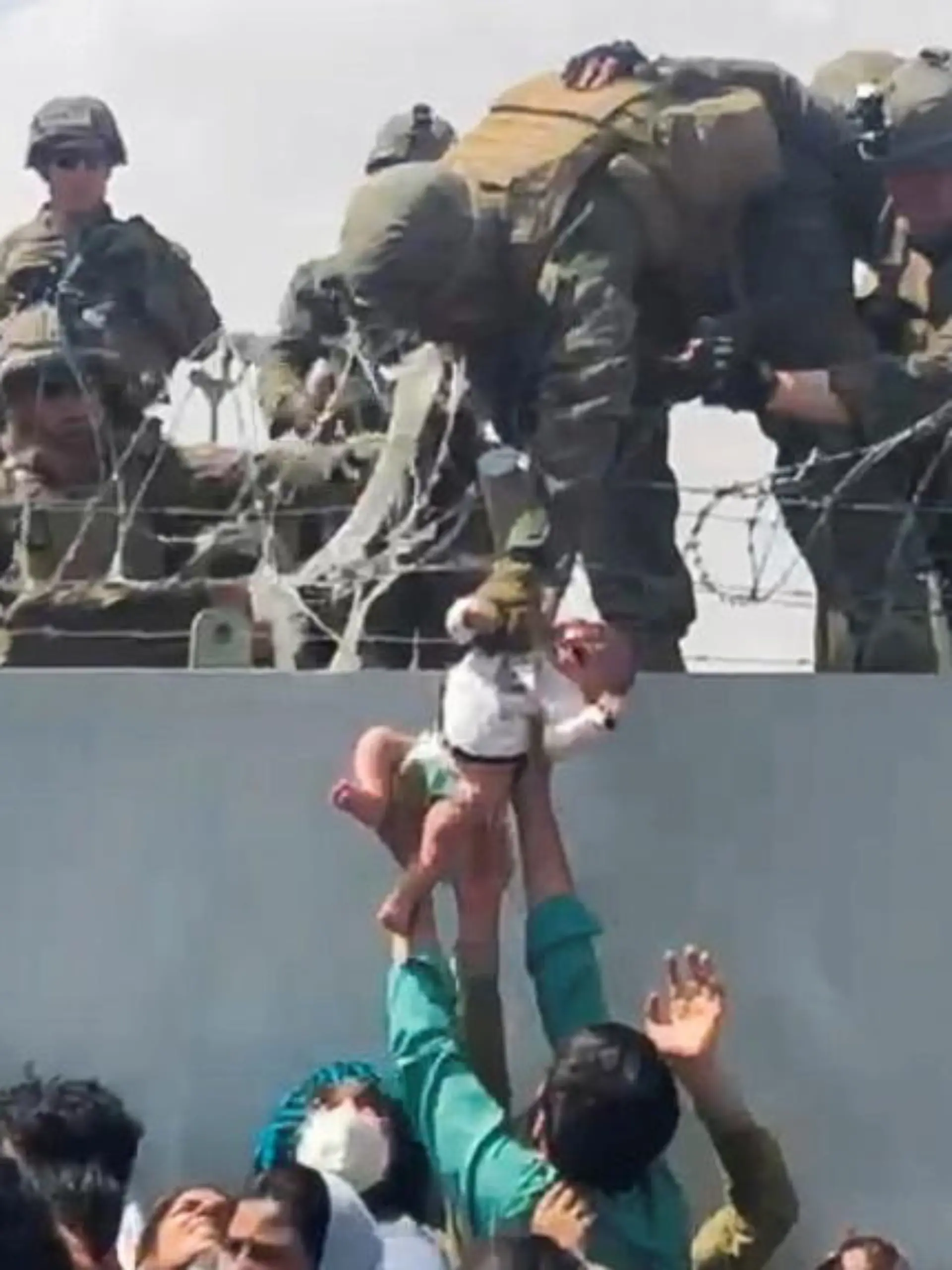 FILE PHOTO: A baby is handed over to the American army over the perimeter wall of the airport for it to be evacuated, in Kabul, Afghanistan, August 19, 2021. OMAR HAIDARI/via REUTERS/File Photo