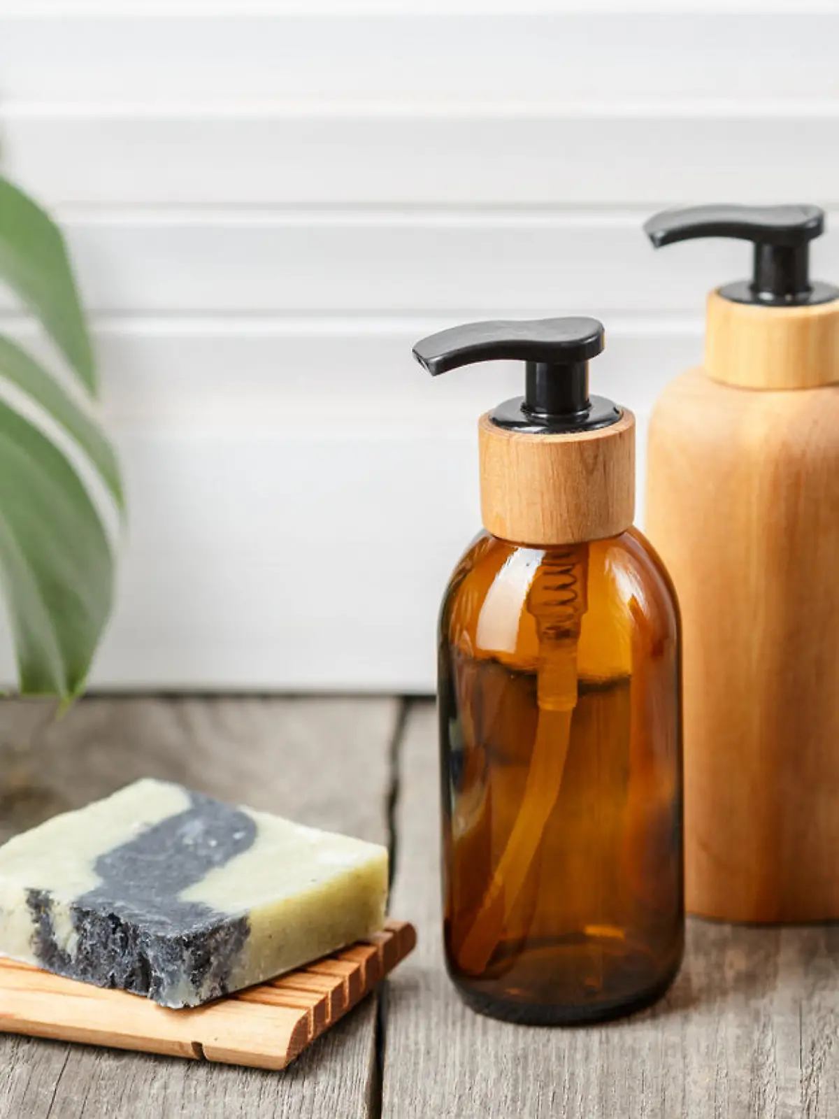 Wooden and glass bathroom accessories without label. Soap bar dish and liquid soap pump dispensers on wooden background