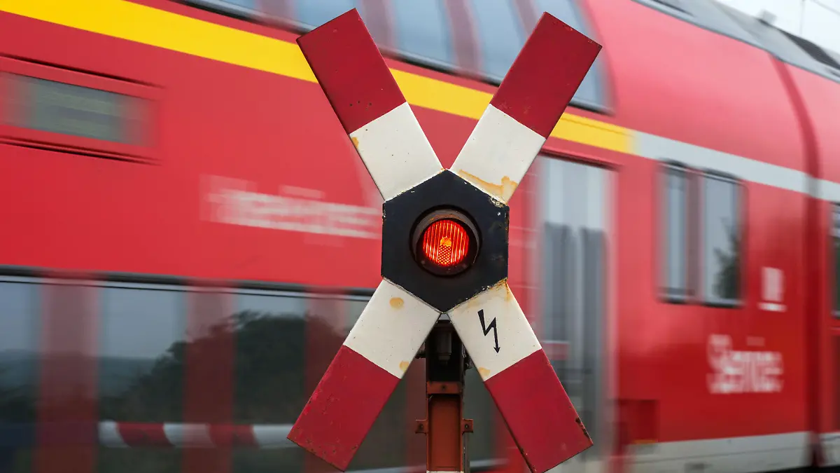 ARCHIV - Ein Personenzug fährt am 16.10.2014 in der Nähe von Schwerin (Mecklenburg-Vorpommern) an einem Bahnübergang mit einem blinkenden Andreaskreuz vorbei. Foto: Jens Büttner/dpa (zu dpa «Lokführer streiken über das Wochenende» vom 17.10.2014) +++(c) dpa - Bildfunk+++
