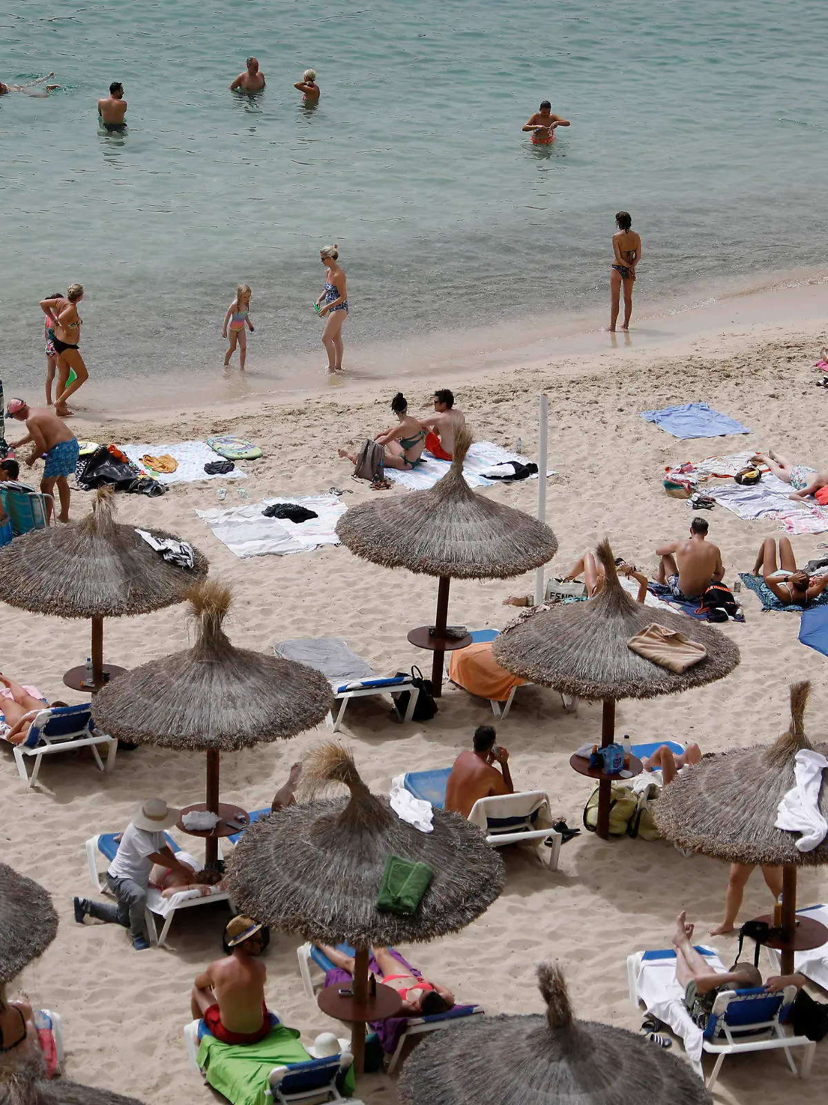 10.08.2021, Spanien, Calvia: Menschen sonnen sich am Strand von Puerto Portals. Foto: Clara Margais/dpa +++ dpa-Bildfunk +++