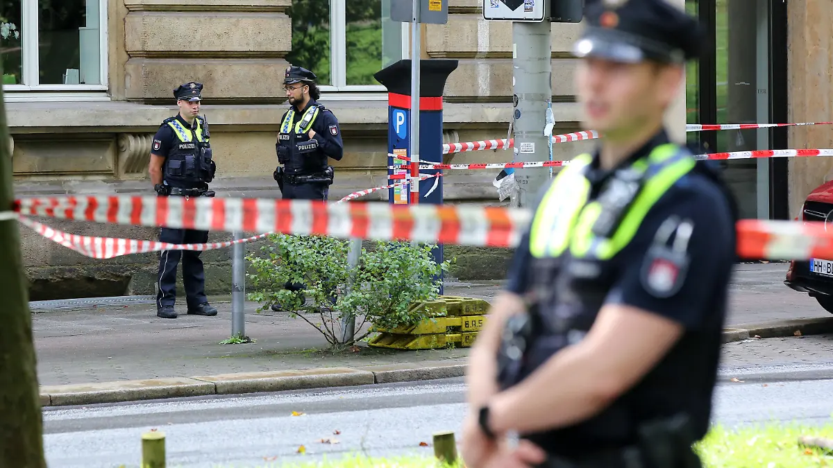 20.08.2021, Hamburg: Einsatzkräfte stehen an einer Polizeiabsperrung auf dem Gorch-Fock-Wall. Zeugen haben am Freitag im Hamburger Zentrum Schüsse gehört - ein großer Polizeieinsatz ist angelaufen. Im Bereich Gorch-Fock-Wall waren offenbar Schüsse gefallen, sagte eine Polizeisprecherin zu entsprechenden Medienberichten. Umfassende Fahndungsmaßnahmen laufen. Foto: Bodo Marks/dpa +++ dpa-Bildfunk +++
