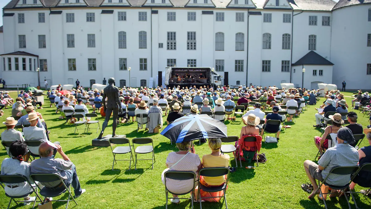 ARCHIV - 08.08.2020, Schleswig-Holstein, Schleswig: Besucher sitzen während eines Konzertes im Rahmen des Schleswig-Holstein Musik Festivals (SHMF) vor dem Schloss Gottorf in der Sonne. Auf diesem Gelände finden am 28.08.2021 ein Festakt und ein Bürgerfest zum 75-jährigen Bestehen des Landes Schleswig-Holstein statt (zu dpa «Festakt und Bürgerfest auf Schloss Gottorf zum 75. Landesgeburtstag»). Foto: Gregor Fischer/dpa +++ dpa-Bildfunk +++