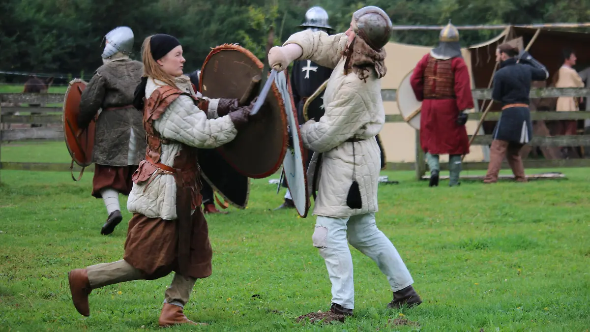 Zwei Personen in Mittelalter-Tracht duellieren sich im Schwertkampf.