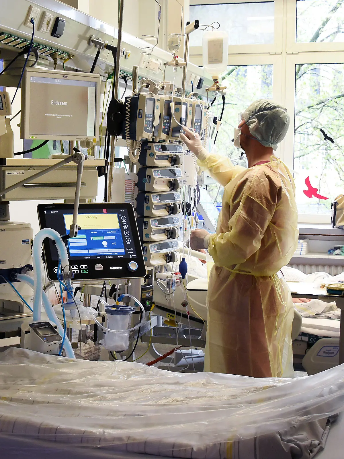 12.05.2021, Sachsen-Anhalt, Halle (Saale): Im Krankenhaus St. Elisabeth und St. Barbara Halle/Saale überprüft der Fachkrankenpfleger für Anästhesie und Intensivpflege Friedrich neben einen leeren Bett auf der Interdisziplinären Intensivstation mit Covid-19-Bereich einen Infusions-und Spritzenpumpenturm am Bett eines Patienten. Auf der Station ist seit dem heutigen Tag eine deutliche Entspannung zu spüren, was die Belegung durch Patienten mit Covid-19 betrifft. Foto: Waltraud Grubitzsch/dpa-Zentralbild/dpa +++ dpa-Bildfunk +++