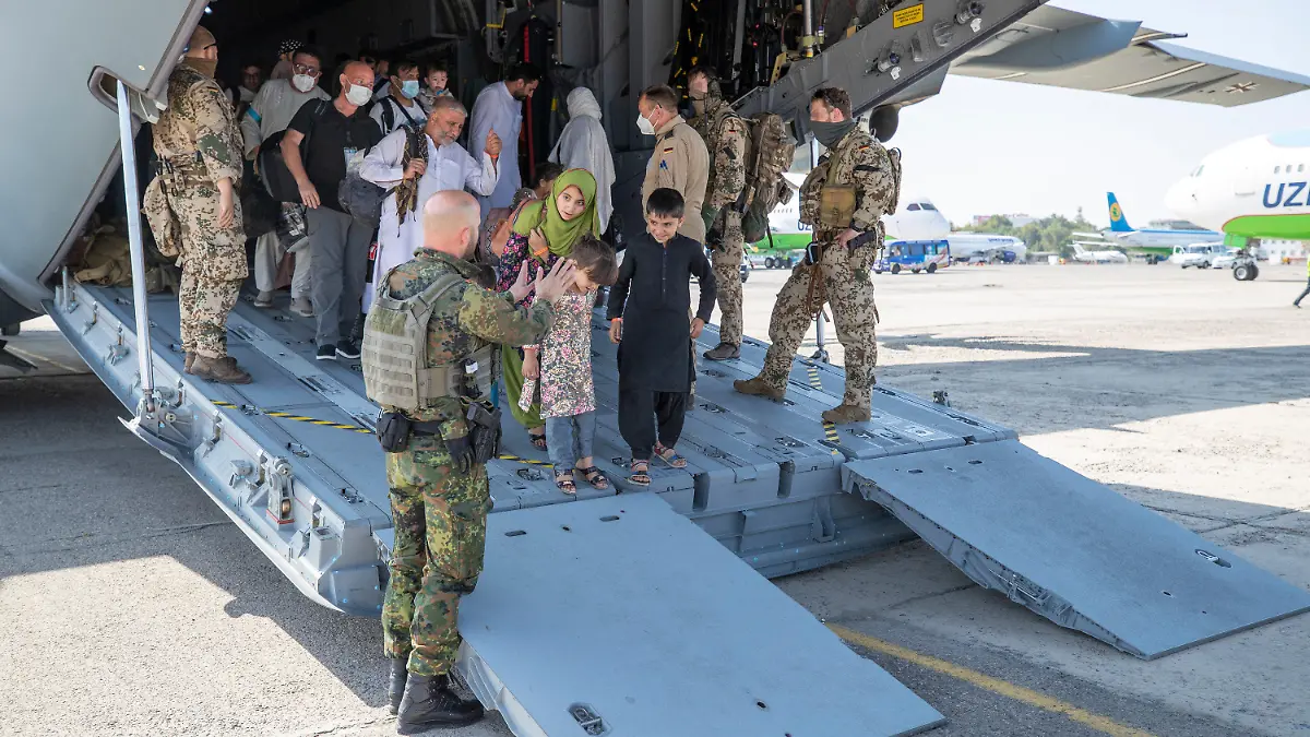 HANDOUT - 18.08.2021, Usbekistan, Taschkent: Kurz nach der Landung werden die Evakuierten von deutschen Sicherungskräften aus dem Airbus A400M geleitet. Nach der Machtübernahme der Taliban in Afghanistan hat die Bundeswehr unter schwierigsten Bedingungen eine Luftbrücke zur Evakuierung von Deutschen und Afghanen eingerichtet. Foto: Marc Tessensohn/Bundeswehr/dpa - ACHTUNG: Nur zur redaktionellen Verwendung und nur mit vollständiger Nennung des vorstehenden Credits +++ dpa-Bildfunk +++