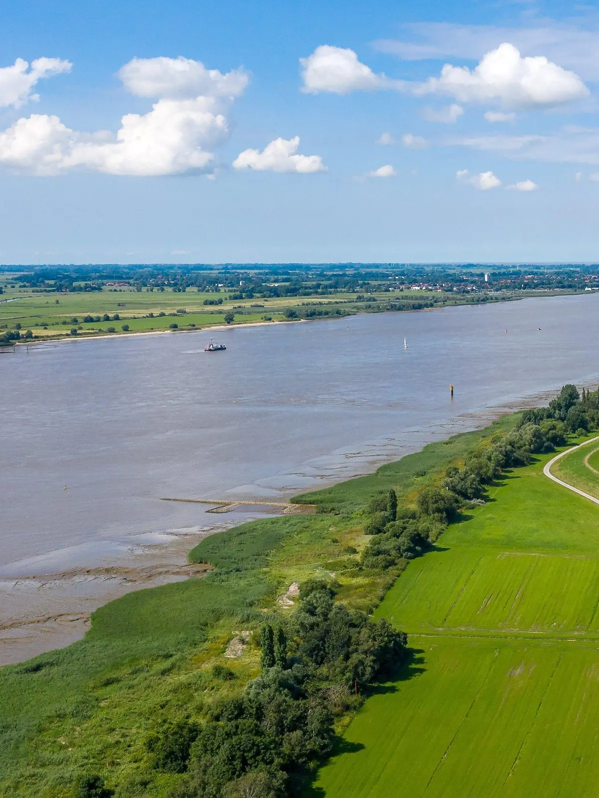 04.08.2021, Niedersachsen, Loxstedt: Die Weser zwischen Brake und Nordenham (Luftaufnahme mit einer Drohne). Um das Projekt der Weservertiefung wird seid über einem Jahrzehnt gestritten, auch vor Gericht. Es geht um die Vertiefung der Weser von der Nordsee nach Bremerhaven und von Bremerhaven weseraufwärts bis nach Brake. Umweltschützer warnen vor katastrophalen Folgen, die Wirtschaft hält das Projekt aus Wettbewerbsgründen für dringend geboten. Foto: Sina Schuldt/dpa +++ dpa-Bildfunk +++