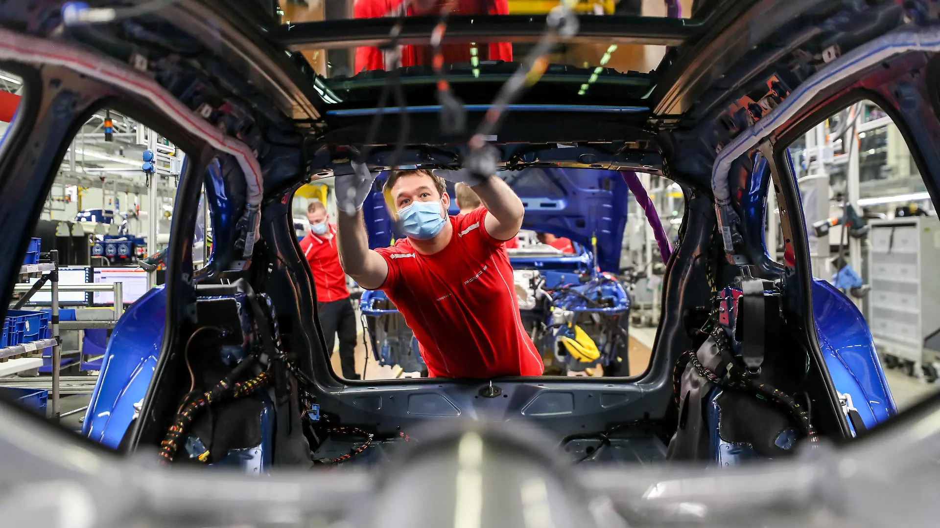 ARCHIV - 07.05.2020, Sachsen, Leipzig: Ein Mitarbeiter von Porsche arbeitet mit Mundschutz in der Montage an einem Macan. Die Coronakrise hat nach Einschätzung der Organisation für wirtschaftliche Zusammenarbeit und Entwicklung (OECD) schlimmere Auswirkungen auf die Wirtschaft als die Finanzkrise 2009. Foto: Jan Woitas/dpa-Zentralbild/dpa +++ dpa-Bildfunk +++