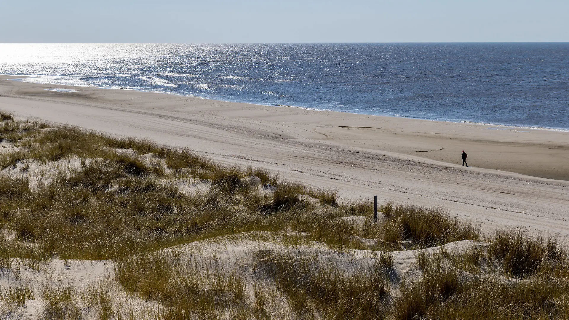 08.04.2019, Schleswig-Holstein, Wenningstedt/Sylt: Ein Mann läuft bei strahlendem Sonnenschein auf der Insel Sylt über einen ansonsten menschenleeren Strand Foto: Axel Heimken/dpa +++ dpa-Bildfunk +++