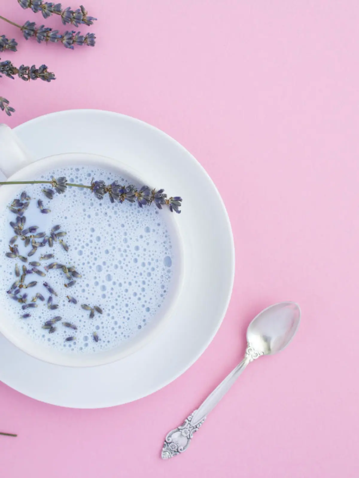 Top view of lavender moon milk in the white cup on the pink surface. Copy space.
