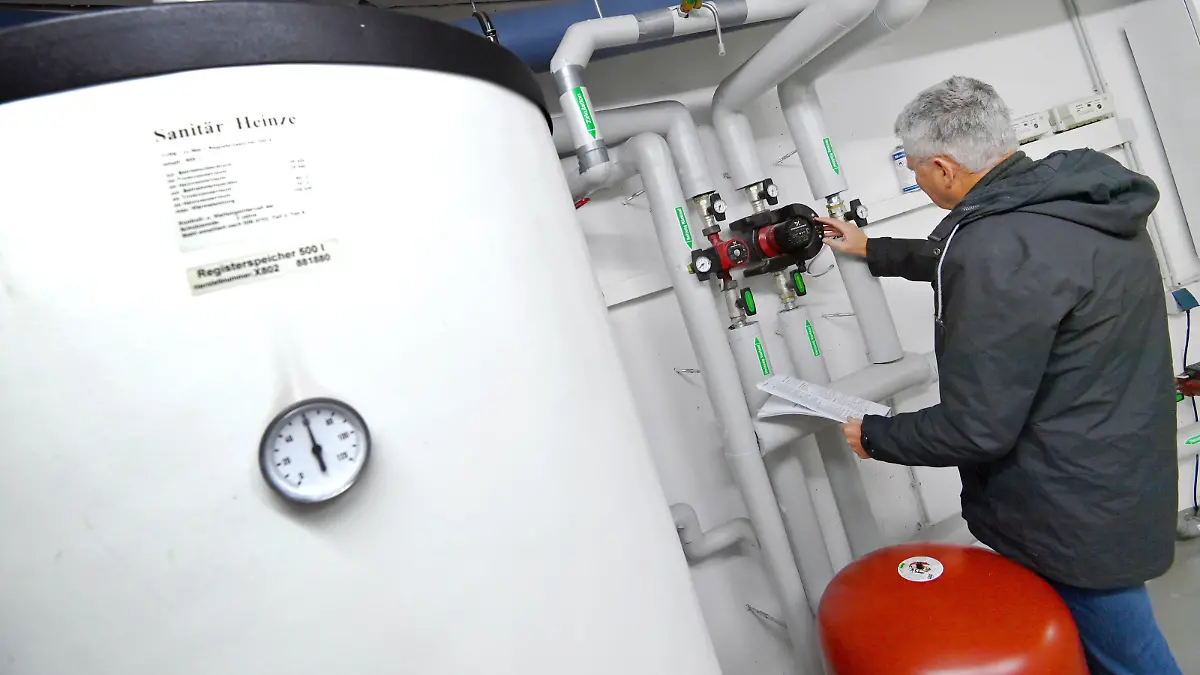 Themenfoto Gasheizung: Mann steht im Heizungskeller und nimmt Einstellungen an Umwaelzpumpen vor. ?