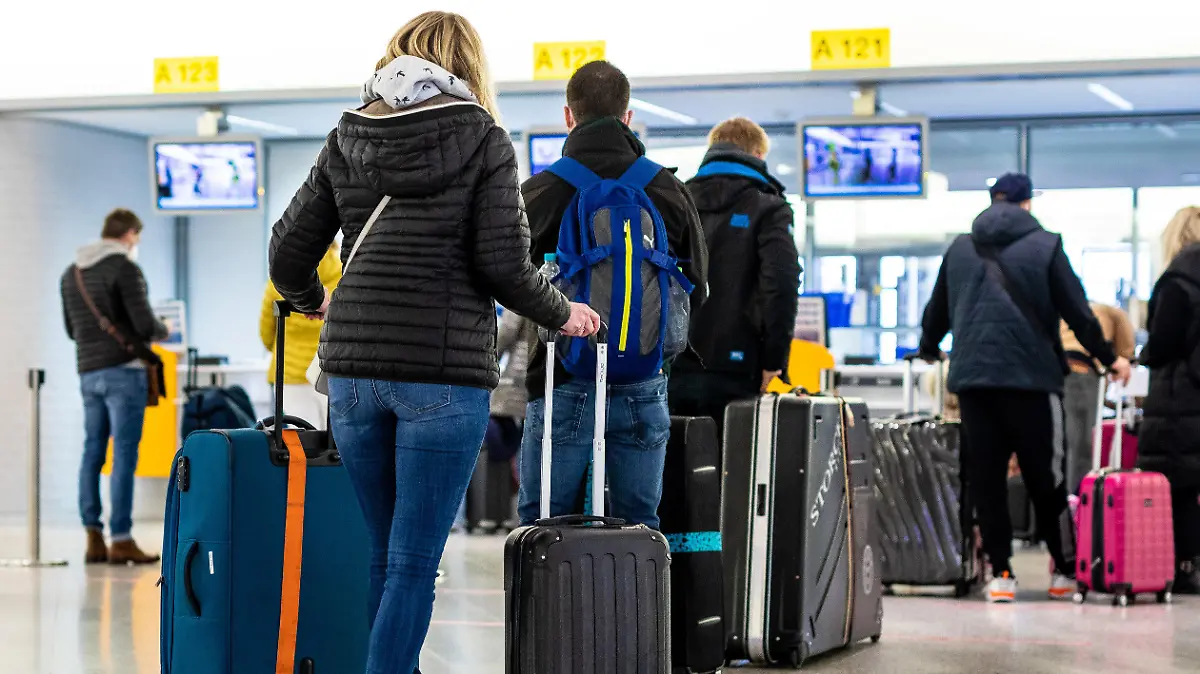 21.03.2021, Niedersachsen, Langenhagen: Fluggäste mit dem Reiseziel Mallorca stehen im Flughafen Hannover-Langenhagen am Check-in. Von Hannover aus fliegt der größte Reisekonzern Tui ab Sonntag nach langer Zwangspause wieder die ersten Urlauber nach Mallorca. Das Auslaufen der Reisewarnung für die Balearen macht dies möglich. Foto: Moritz Frankenberg/dpa +++ dpa-Bildfunk +++