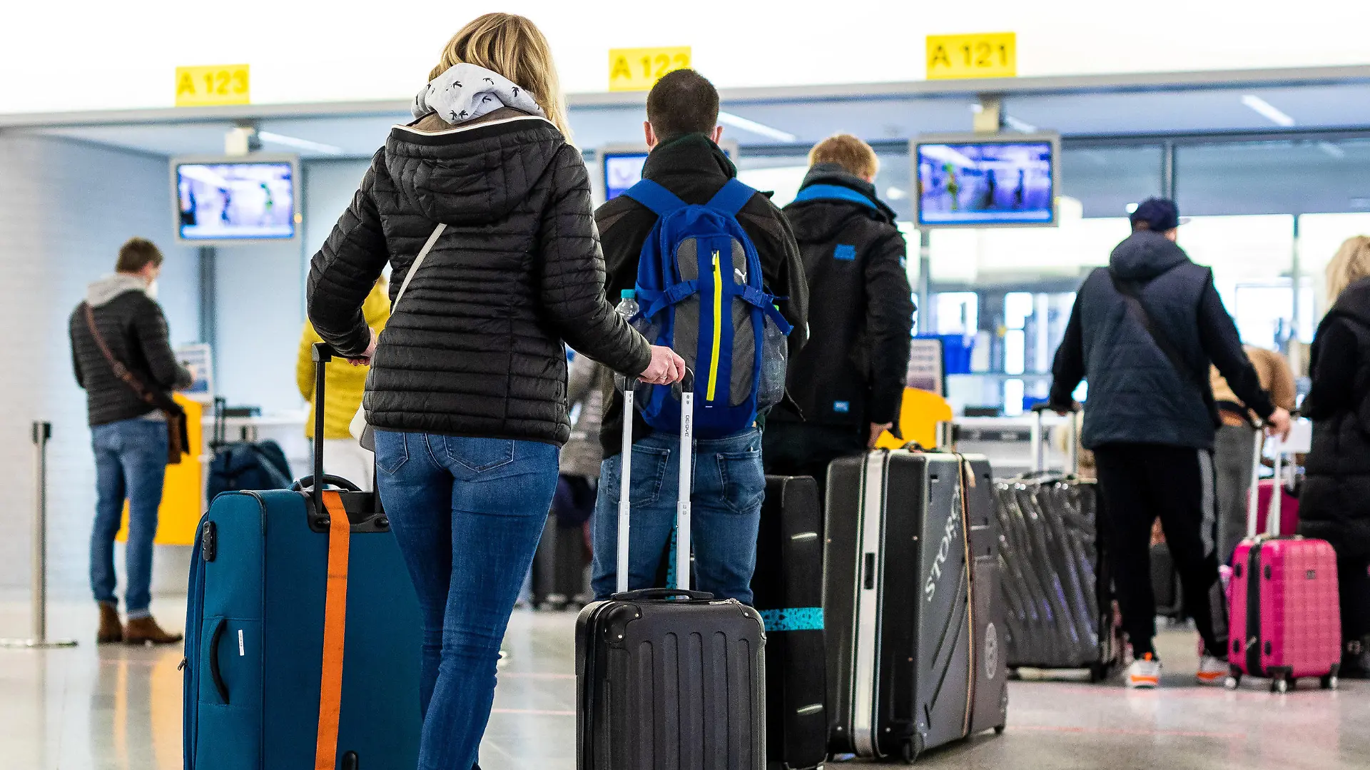 21.03.2021, Niedersachsen, Langenhagen: Fluggäste mit dem Reiseziel Mallorca stehen im Flughafen Hannover-Langenhagen am Check-in. Von Hannover aus fliegt der größte Reisekonzern Tui ab Sonntag nach langer Zwangspause wieder die ersten Urlauber nach Mallorca. Das Auslaufen der Reisewarnung für die Balearen macht dies möglich. Foto: Moritz Frankenberg/dpa +++ dpa-Bildfunk +++