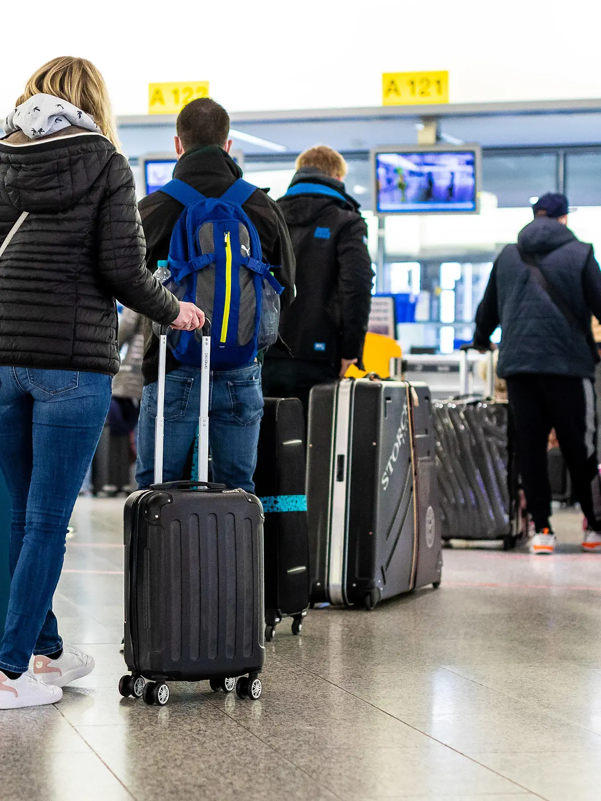 21.03.2021, Niedersachsen, Langenhagen: Fluggäste mit dem Reiseziel Mallorca stehen im Flughafen Hannover-Langenhagen am Check-in. Von Hannover aus fliegt der größte Reisekonzern Tui ab Sonntag nach langer Zwangspause wieder die ersten Urlauber nach Mallorca. Das Auslaufen der Reisewarnung für die Balearen macht dies möglich. Foto: Moritz Frankenberg/dpa +++ dpa-Bildfunk +++