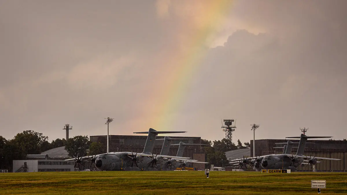 16.08.2021, Niedersachsen, Wunstorf: Ein Regenbogen spannt sich über Transportflugzeugen vom Typ Airbus A400M der Luftwaffe, die auf dem Fliegerhorst Wunstorf in der Region Hannover stehen. Angesichts des rasanten Vormarschs der Taliban in Afghanistan hat die Bundeswehr mit der Evakuierung deutscher Staatsbürger und afghanischer Ortskräfte aus Kabul begonnen. Foto: Moritz Frankenberg/dpa +++ dpa-Bildfunk +++