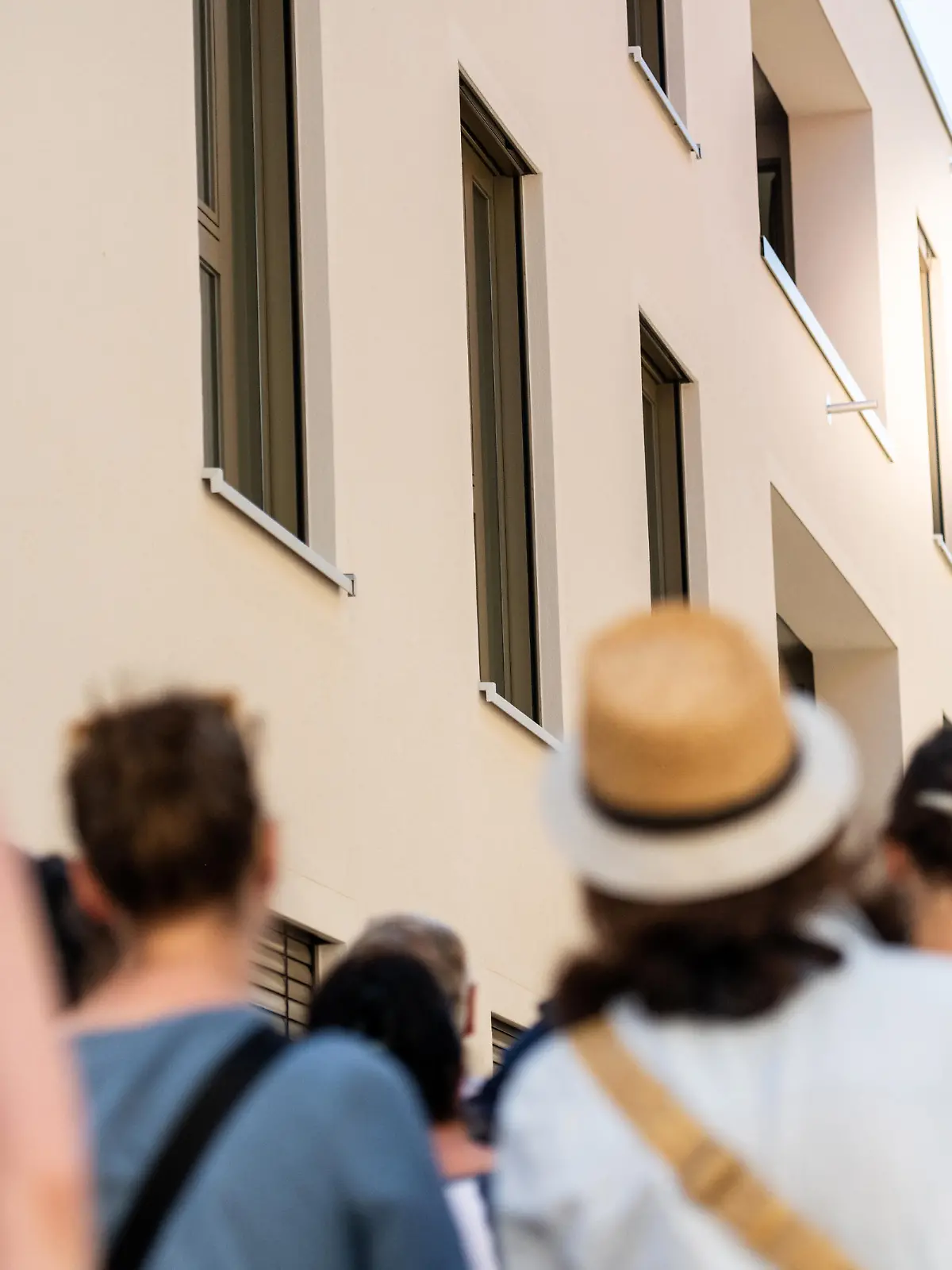 Eine Gruppe Menschen steht vor einem Wohnhaus und wartet auf die Wohnungsbesichtigung.