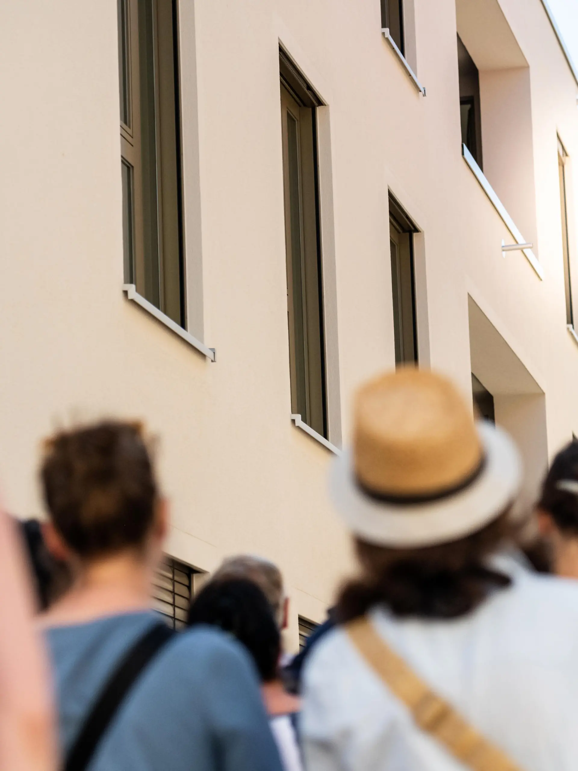 Eine Gruppe Menschen steht vor einem Wohnhaus und wartet auf die Wohnungsbesichtigung.