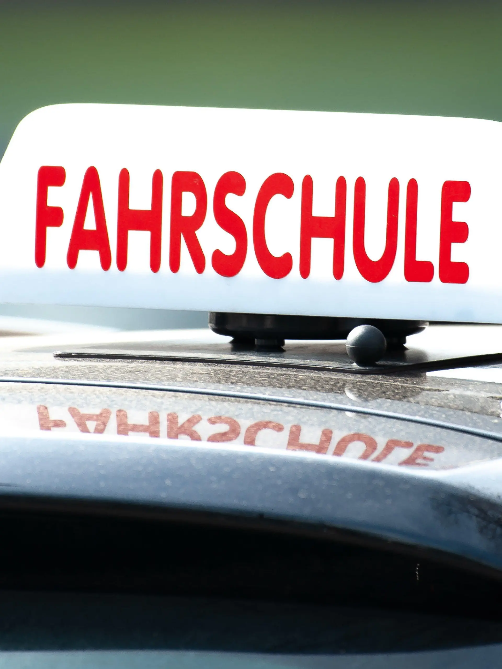 ARCHIV - 13.04.2018, Göttingen: Ein Schild mit der Aufschrift «Fahrschule» ist auf einem Fahrschulauto befestigt. (zu dpa: «Fahrlehrer beklagen Terminmangel für Führerscheinprüfungen») Foto: Swen Pförtner/dpa +++ dpa-Bildfunk +++