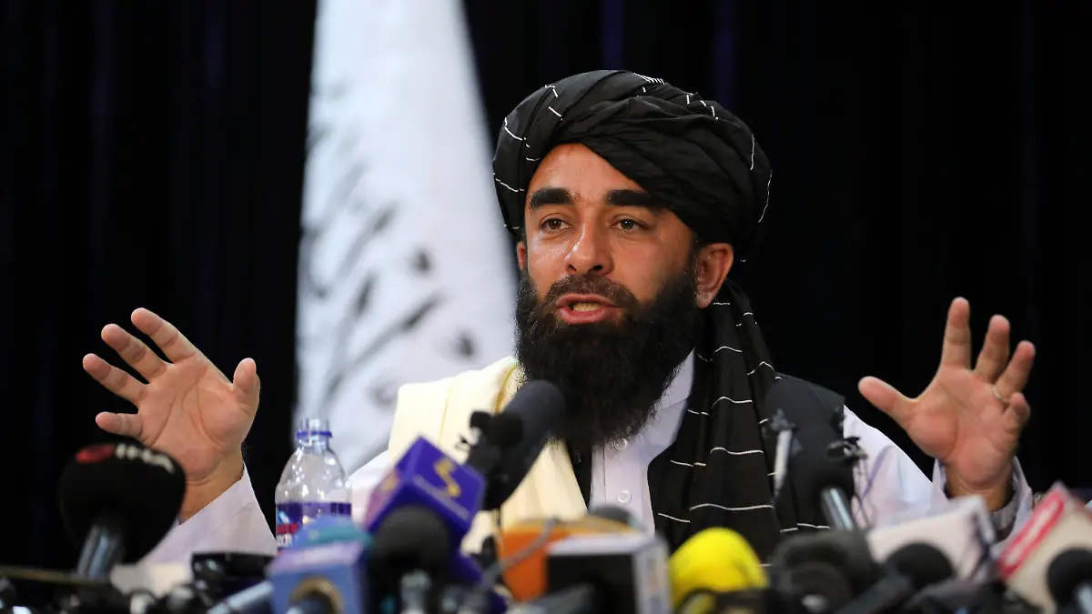 In front of a Taliban flag, Taliban spokesman Zabihullah Mujahid speaks at at his first news conference, in Kabul, Afghanistan, Tuesday, Aug. 17, 2021. For years, Mujahid had been a shadowy figure issuing statements on behalf of the militants. Mujahid vowed Tuesday that the Taliban would respect women's rights, forgive those who resisted them and ensure a secure Afghanistan as part of a publicity blitz aimed at convincing world powers and a fearful population that they have changed. (AP Photo/Rahmat Gul)