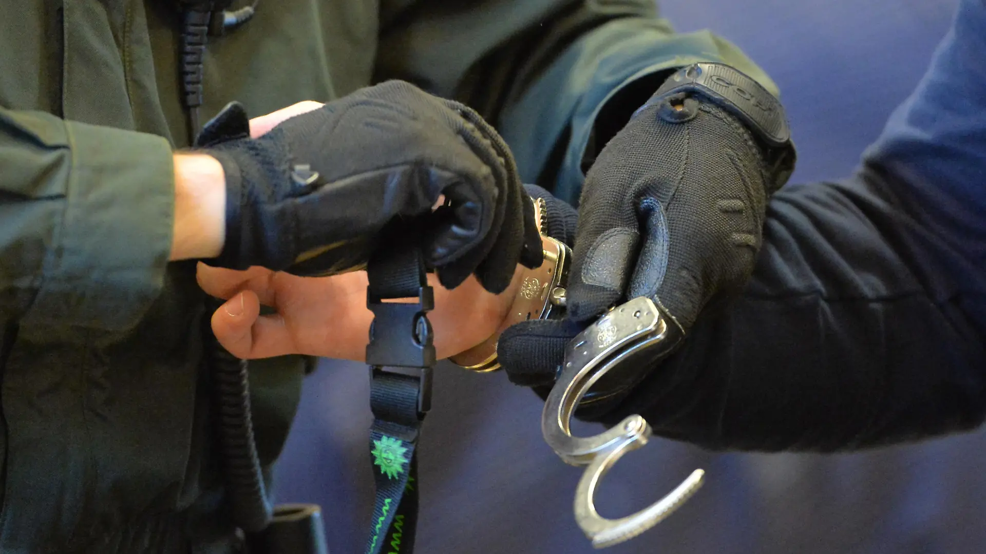 Ein Polizeibeamter nimmt beim Prozessbeginn gegen eine Thüringer Straßengang am 10.10.2013 in Erfurt (Thüringen) im Schwurgerichtssaal des Landgerichtes einem Angeklagten die Handschellen ab. Die insgesamt zehn Mitglieder der Gang im Alter von 22 bis 37 Jahren nannten sich selbst «Saat des Bösen» und sollen zahlreiche Straftaten begangenen haben. Die Bande soll in Suhl, Nordhausen, Weimar, Apolda und Gera aktiv gewesen sein. Bis Ende des Jahres sind 15 Verhandlungstermine angesetzt. Foto: Marc Tirl/dpa | Verwendung weltweit