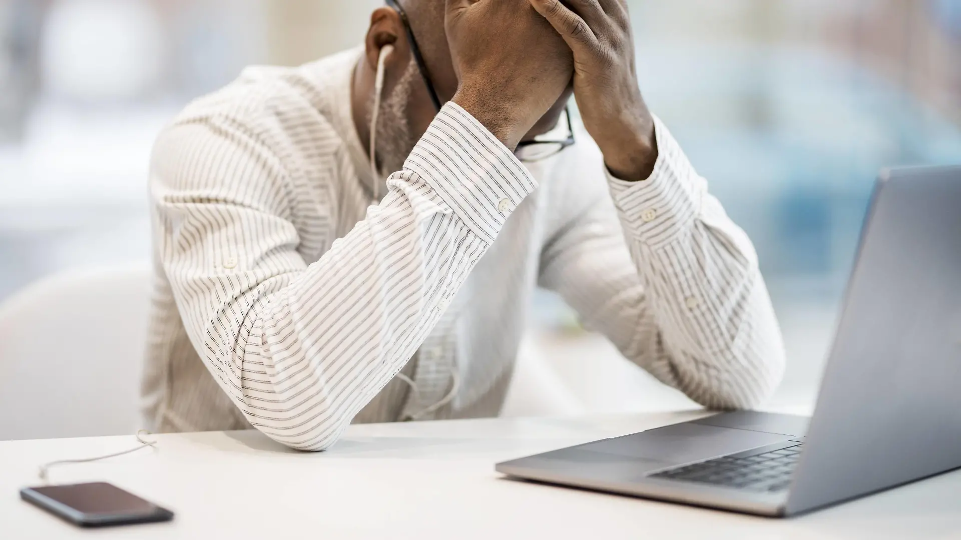 Mature businessman with earphones, smartphoen and laptop sitting with hands on head at desk model released Symbolfoto property released PUBLICATIONxINxGERxSUIxAUTxHUNxONLY FMKF05396