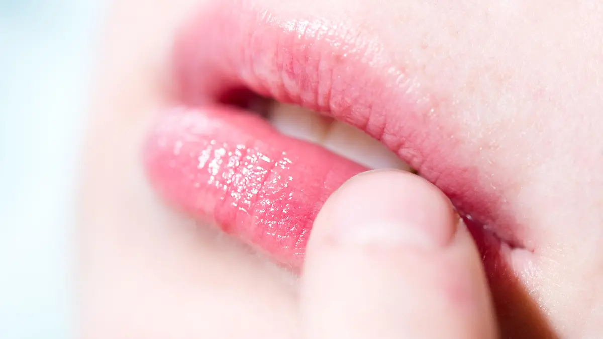 ILLUSTRATION -  Eine Frau befühlt mit einem Finger eine juckende und schmerzende Stelle auf ihrer Lippe. Foto: Franziska Gabbert