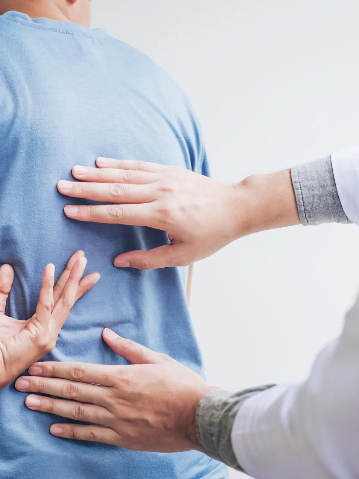 Rücken eines Patienten wird von einem Arzt abgetastet.