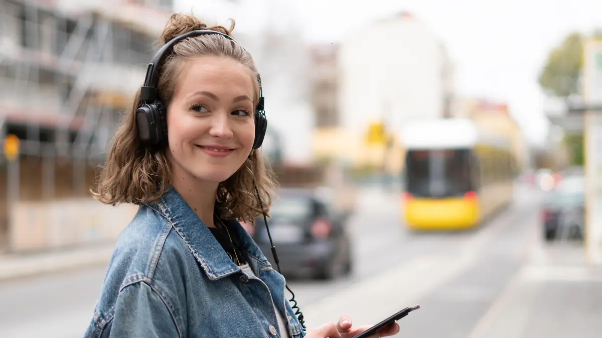 Girl with headphones listening to music waiting for the streetcar