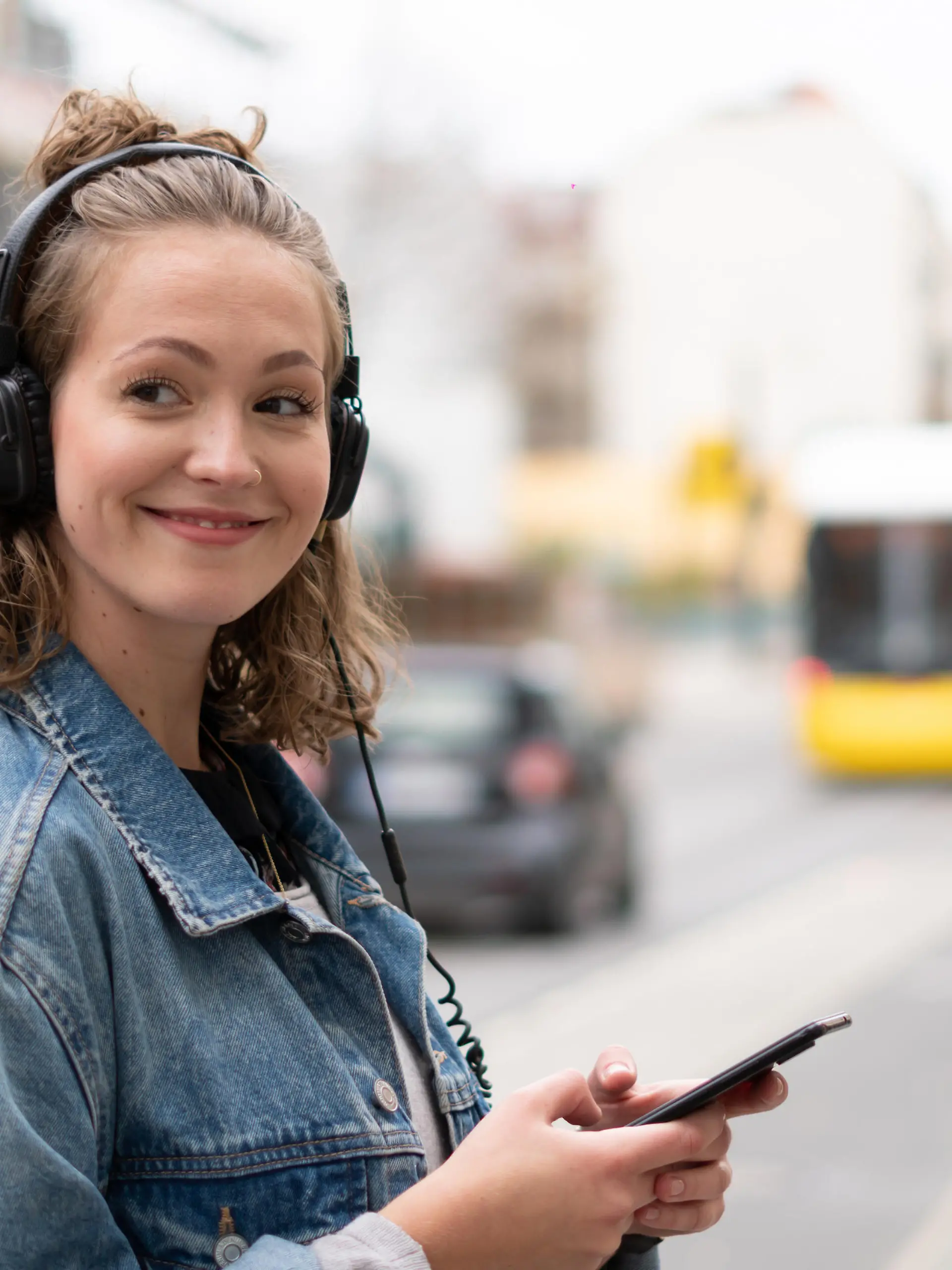 Girl with headphones listening to music waiting for the streetcar