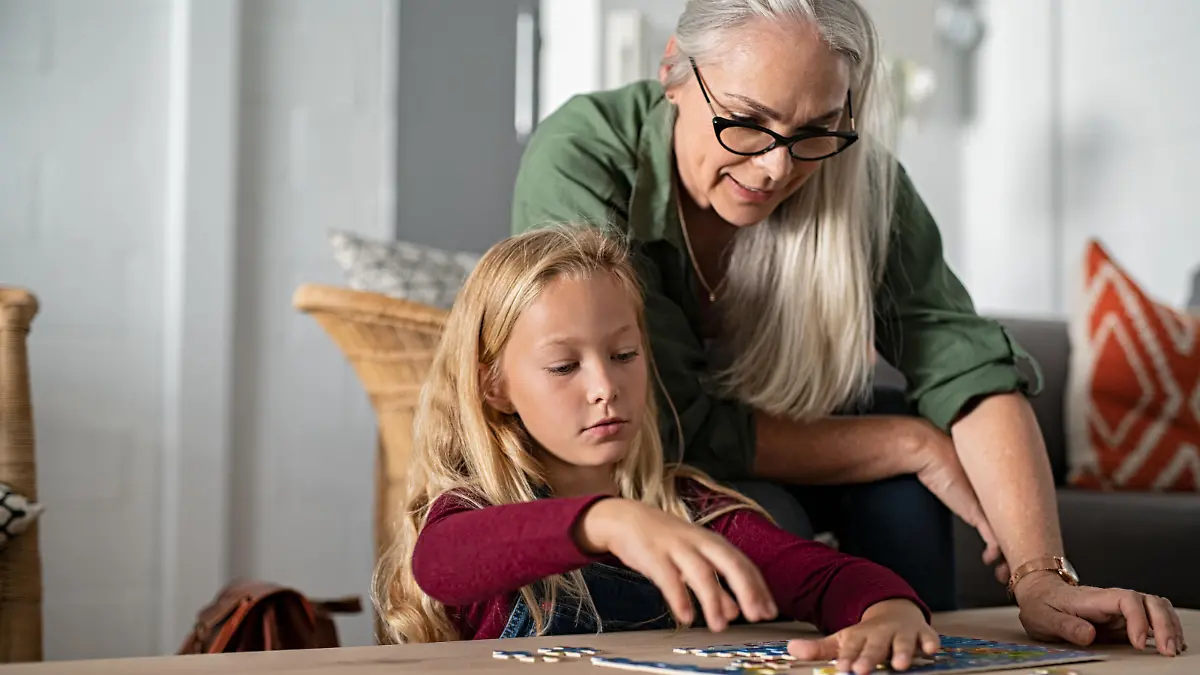 Eine ältere Frau kümmert sich um ihre Tochter, die beiden puzzlen.