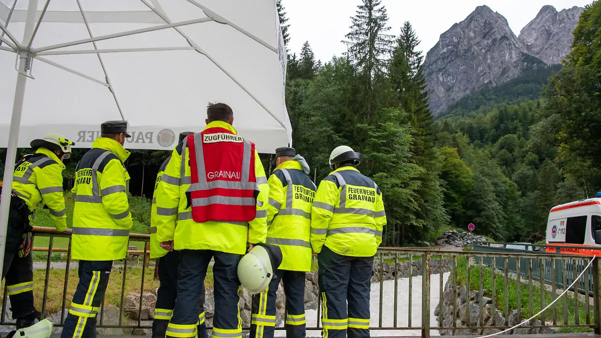 16.08.2021, Bayern, Grainau: Mitglieder der Feuerwehr stehen nach einer Flutwelle in der Höllentalklamm bereit, um im Notfall Opfer aus dem Fluss Hammersbach zu bergen. Am Fuß der Zugspitze liegt die bei Wanderern beliebte Höllentalklamm. Am Montag, den 16. August 2021, rauscht plötzlich eine Flutwelle durch die Klamm. Es gibt mehrere Vermisste. Foto: Peter Kneffel/dpa +++ dpa-Bildfunk +++